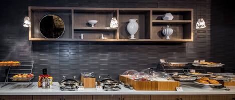 A modern kitchen with a dark brick wall, wooden shelves, and pendant lights.