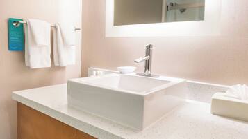 A bathroom with a white sink, a mirror, and a towel rack.