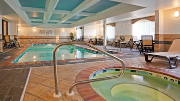 A hotel pool area with two pools, lounge chairs, and a seating area.