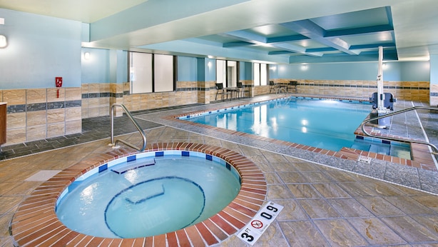 An indoor swimming pool with a hot tub, tiled flooring, and a seating area with chairs and tables. - Holiday Inn Express Hotel & Suites Birmingham - Inverness by IHG (Birmingham)