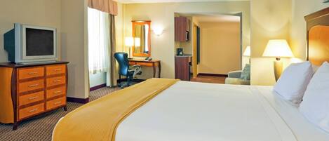 Una habitación de hotel con cama, escritorio, silla, televisor y baño.