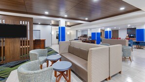 A modern lounge area with a sofa, chairs, and a TV screen. - Holiday Inn Express Hotel & Suites Birmingham - Inverness by IHG (Birmingham)