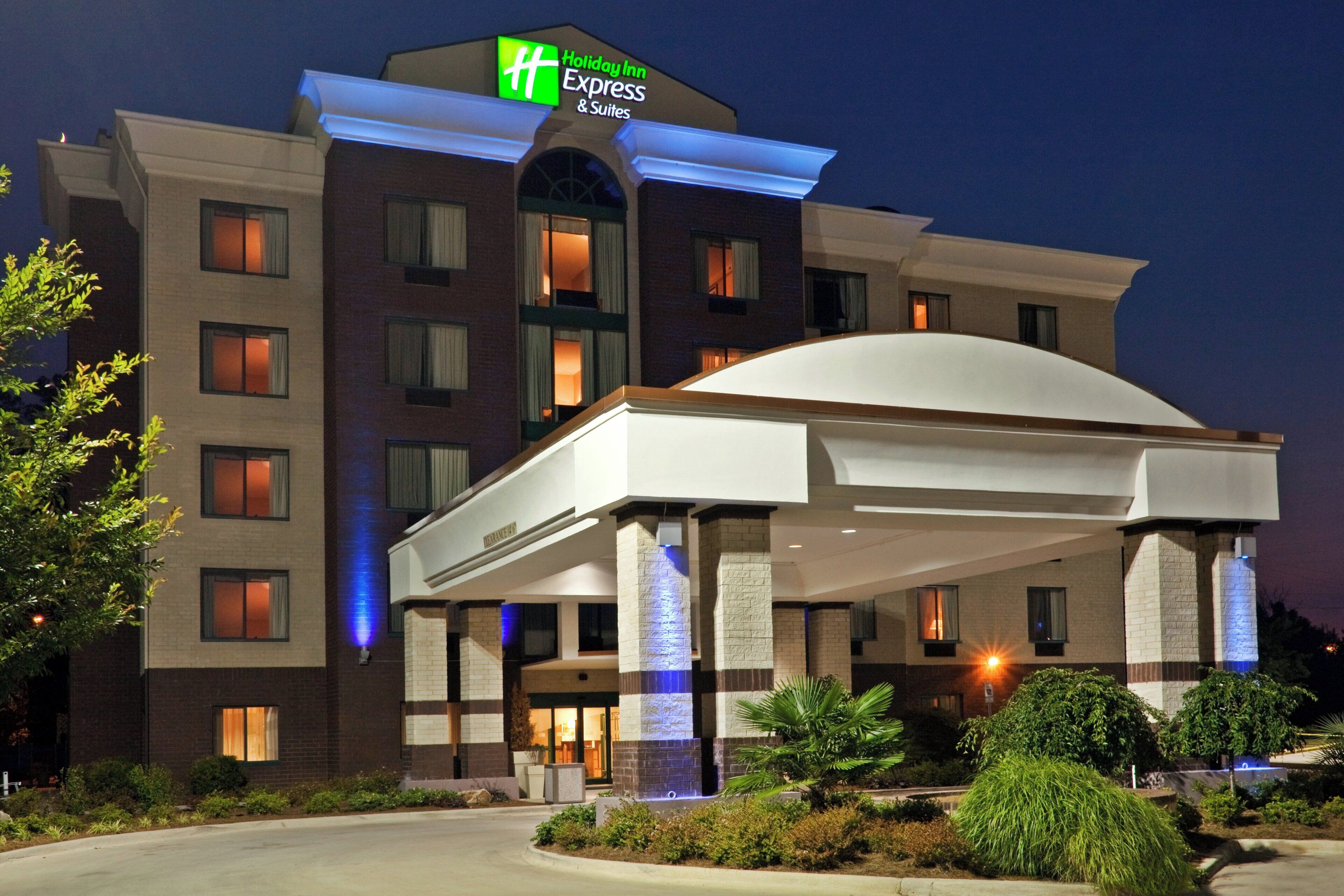 Un hotel Holiday Inn Express con ingresso coperto, diverse finestre e una facciata ben illuminata.