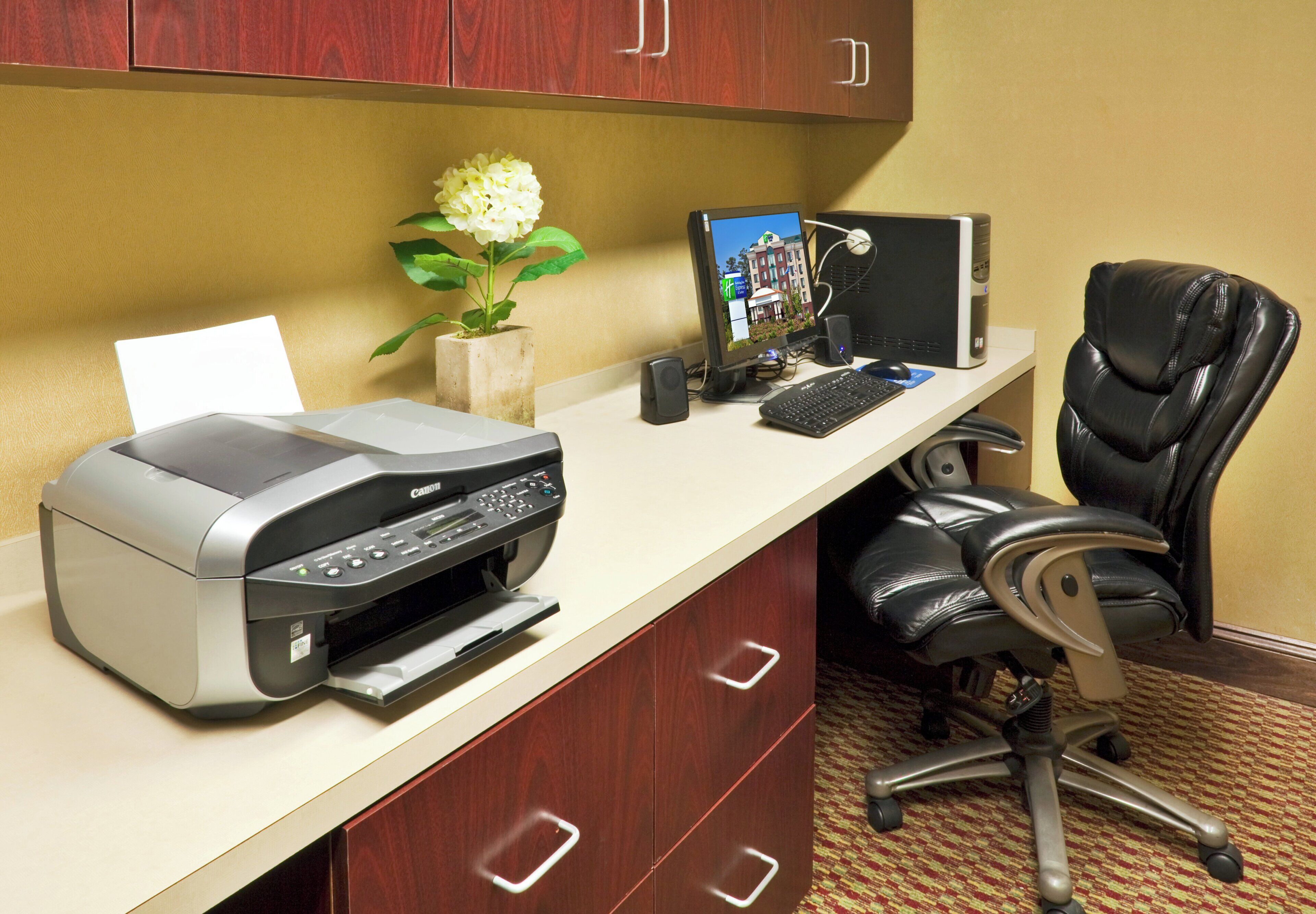 Un espacio de teletrabajo con impresora, computadora y silla de oficina.