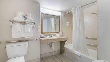 A bathroom with a toilet, sink, mirror, shower, and towel rack.