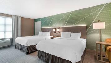 Une chambre d’hôtel avec deux lits, un bureau, une chaise, une lampe et une fenêtre avec des rideaux.