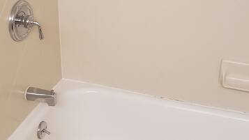 A white bathtub with a grab bar, a faucet, and a towel.