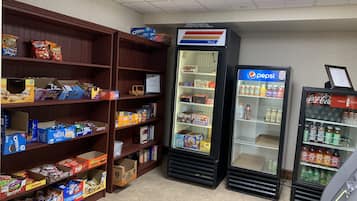 A snack and beverage vending area with various snack boxes and a Pepsi refrigerator.