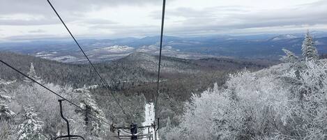 A ski lift with a view of snow-covered trees and distant mountains.