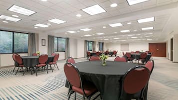A conference room with round tables, chairs, and ceiling lights.