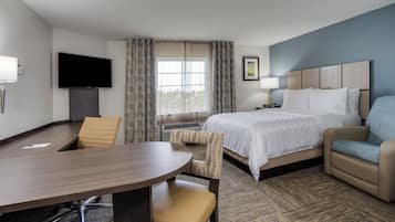 A hotel room with a bed, a desk, a chair, a television, and a window with curtains.