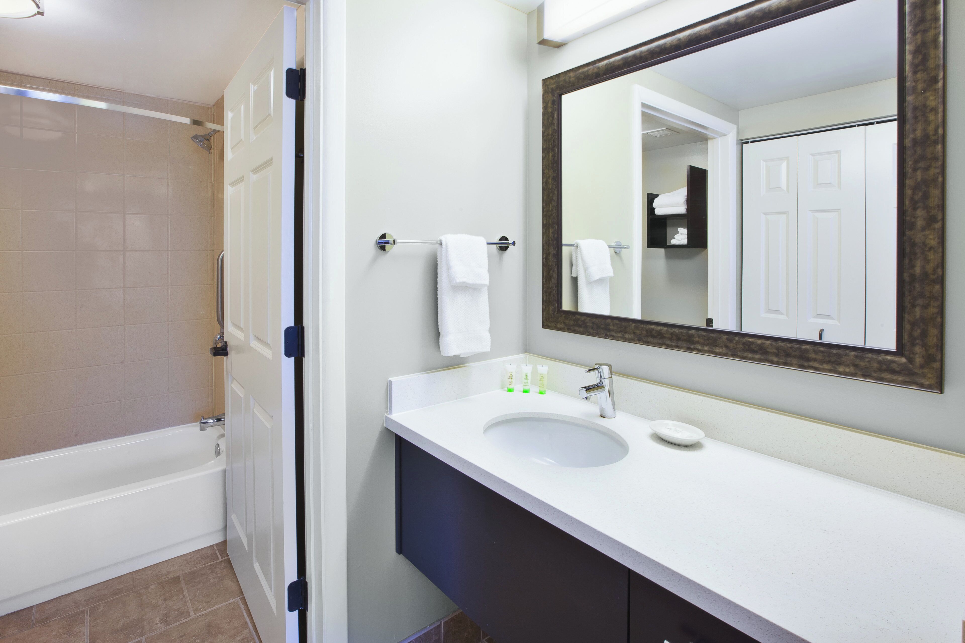A bathroom with a bathtub, a sink, a mirror, and a towel rack.