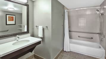 Une salle de bain équipée d’un lavabo, d’un miroir, d’un porte-serviettes et d’une douche à l’italienne avec baignoire.