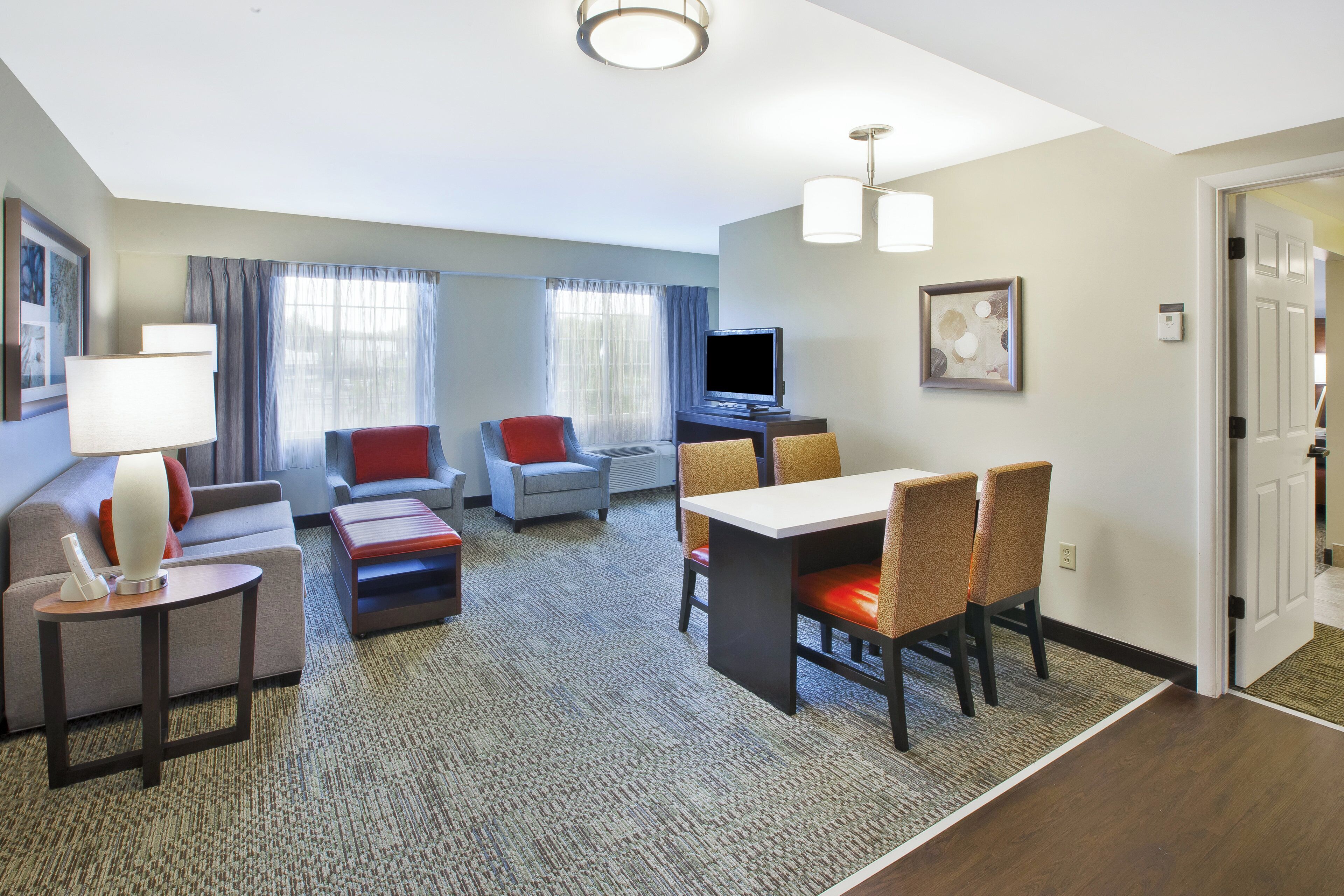 A hotel room with a seating area, a television, and a dining table.