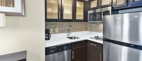 Una cocina moderna con electrodomésticos de acero inoxidable, muebles oscuros y un salpicadero de azulejos.
