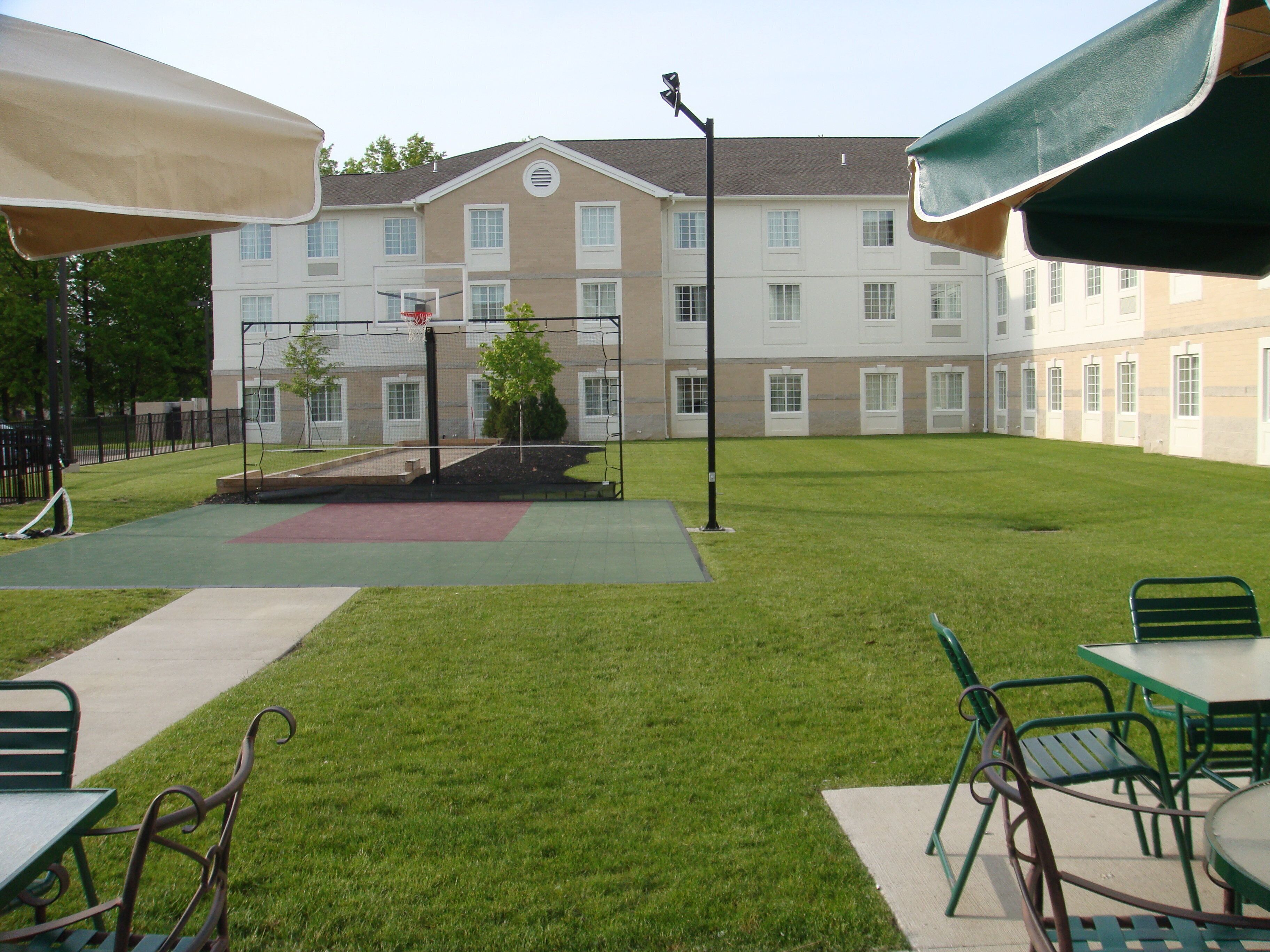 A courtyard with a basketball court, outdoor seating, and a building with multiple windows.
