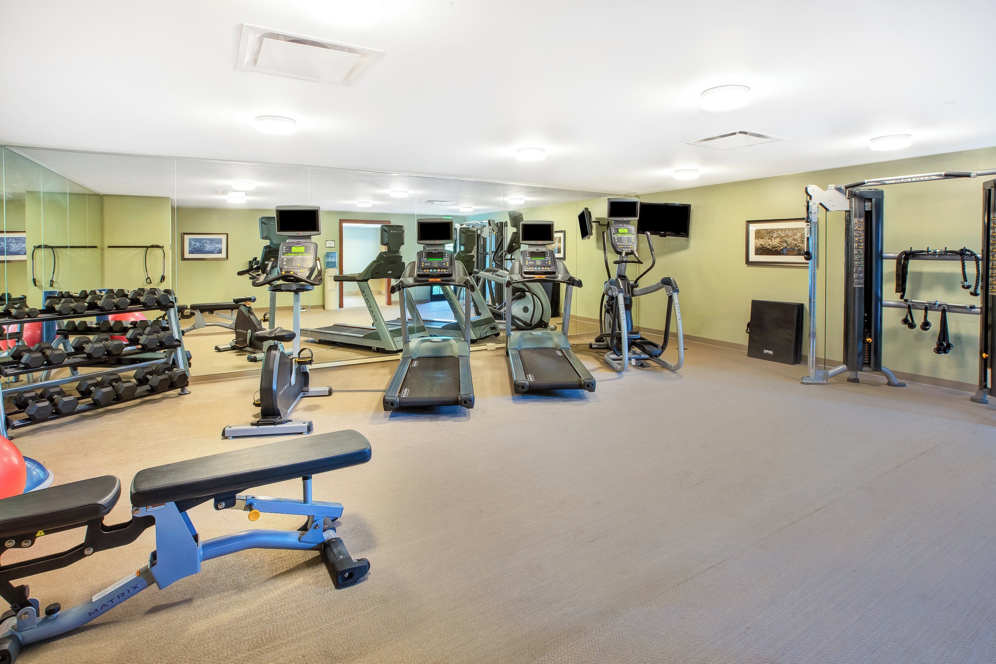 Ein Fitnessstudio mit Laufbändern, Ergometer und Kurzhanteln.