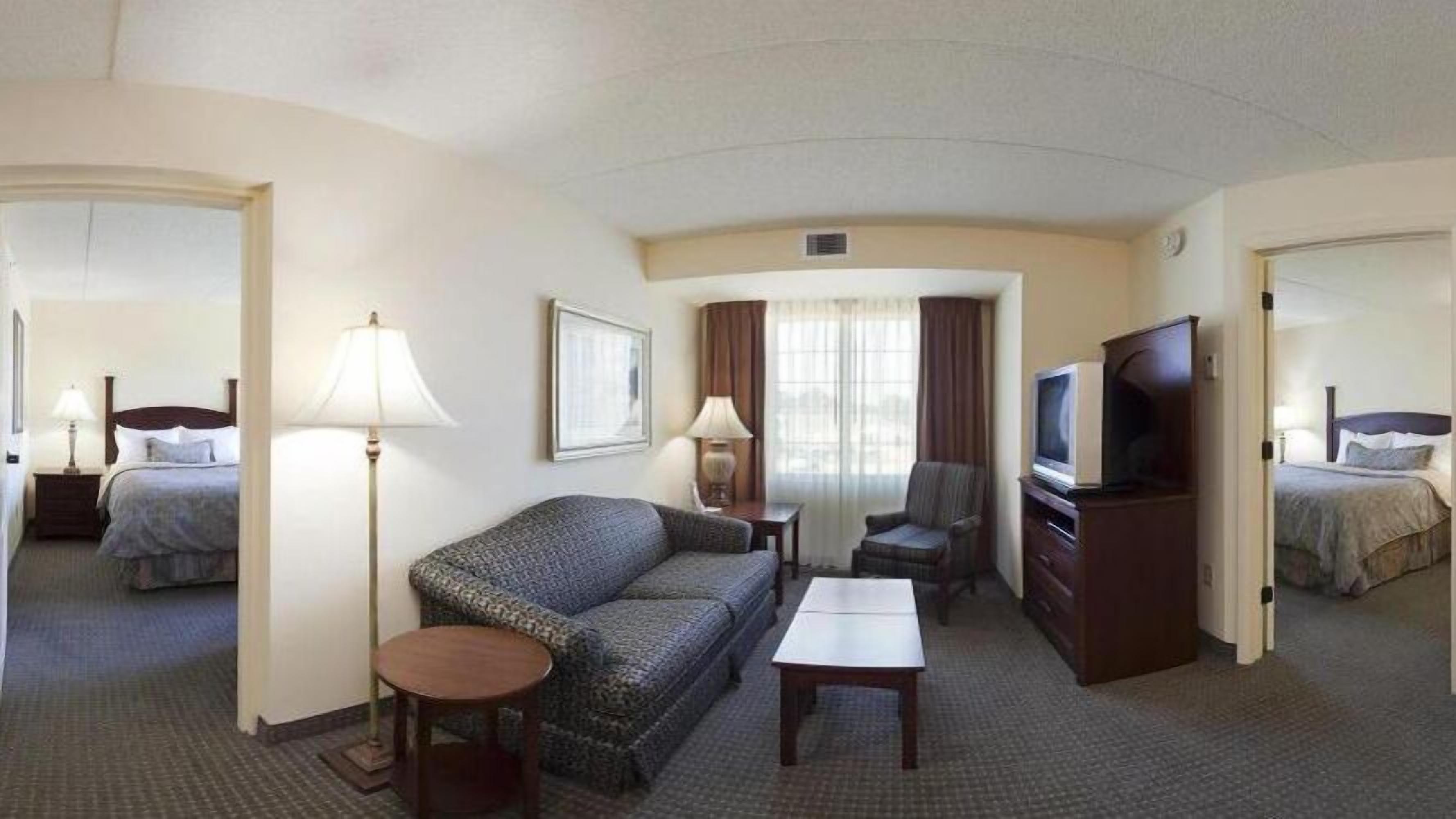 Una habitación de hotel con cama, sofá, televisor, escritorio y una silla.