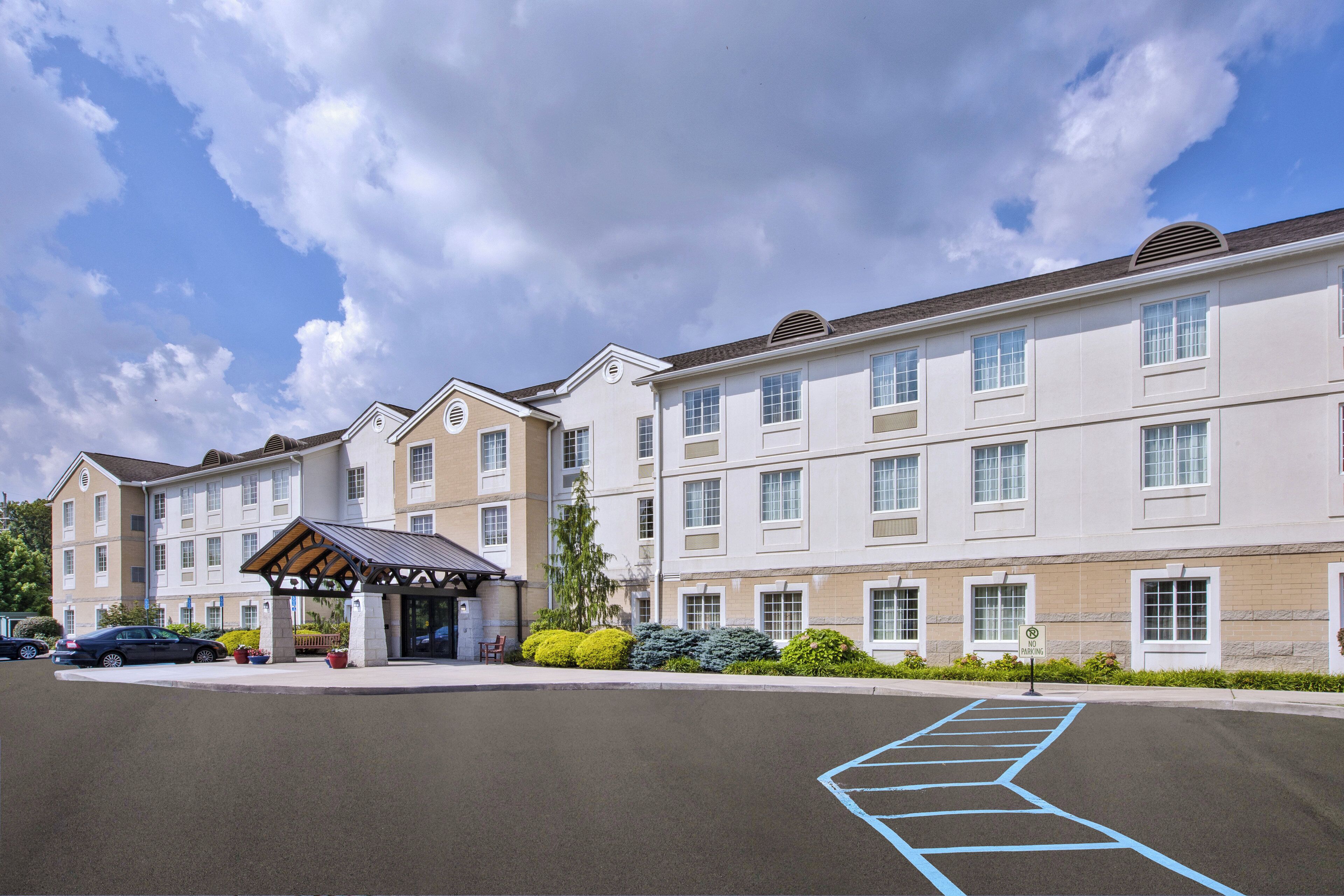 A multi-story hotel with a covered entrance and a parking area.