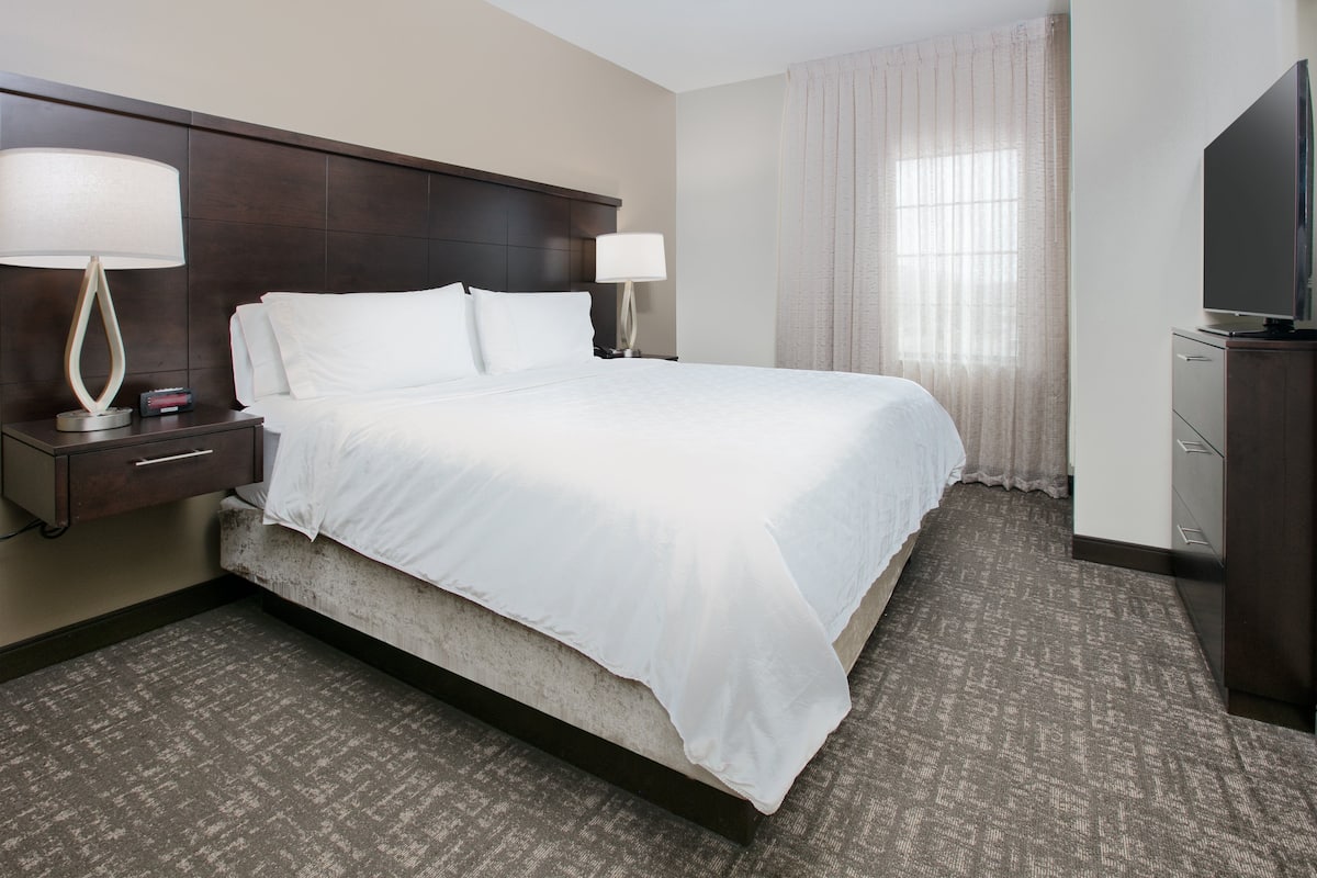 A hotel room with a large bed, two bedside lamps, a TV, and a wardrobe.