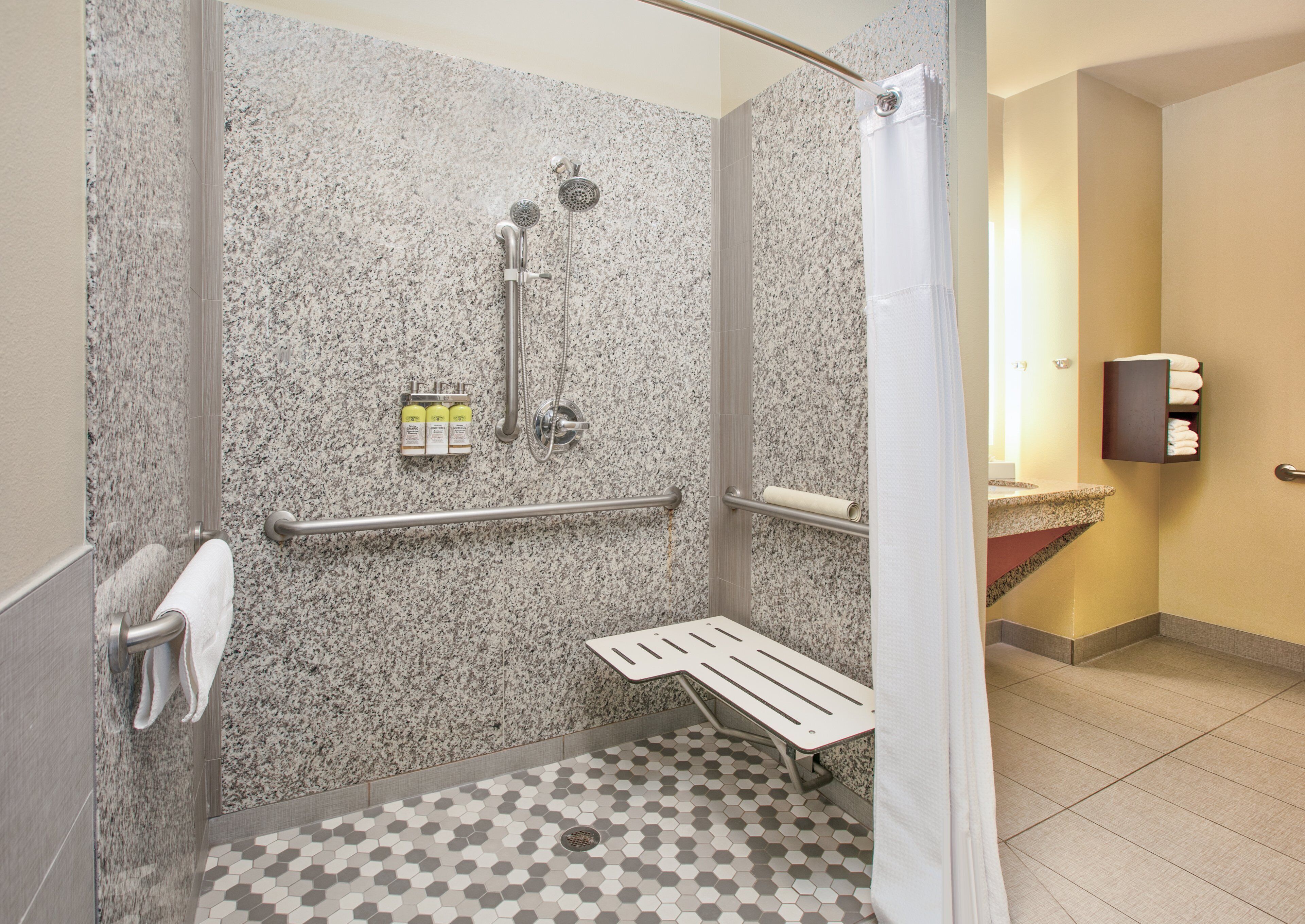 A shower area with a granite wall, a bench, and a towel rack.
