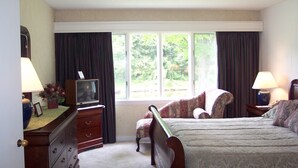 A bedroom with a bed, a dresser, a television, and a chair. - The Inn at the Mountain & Condominiums (Stowe)