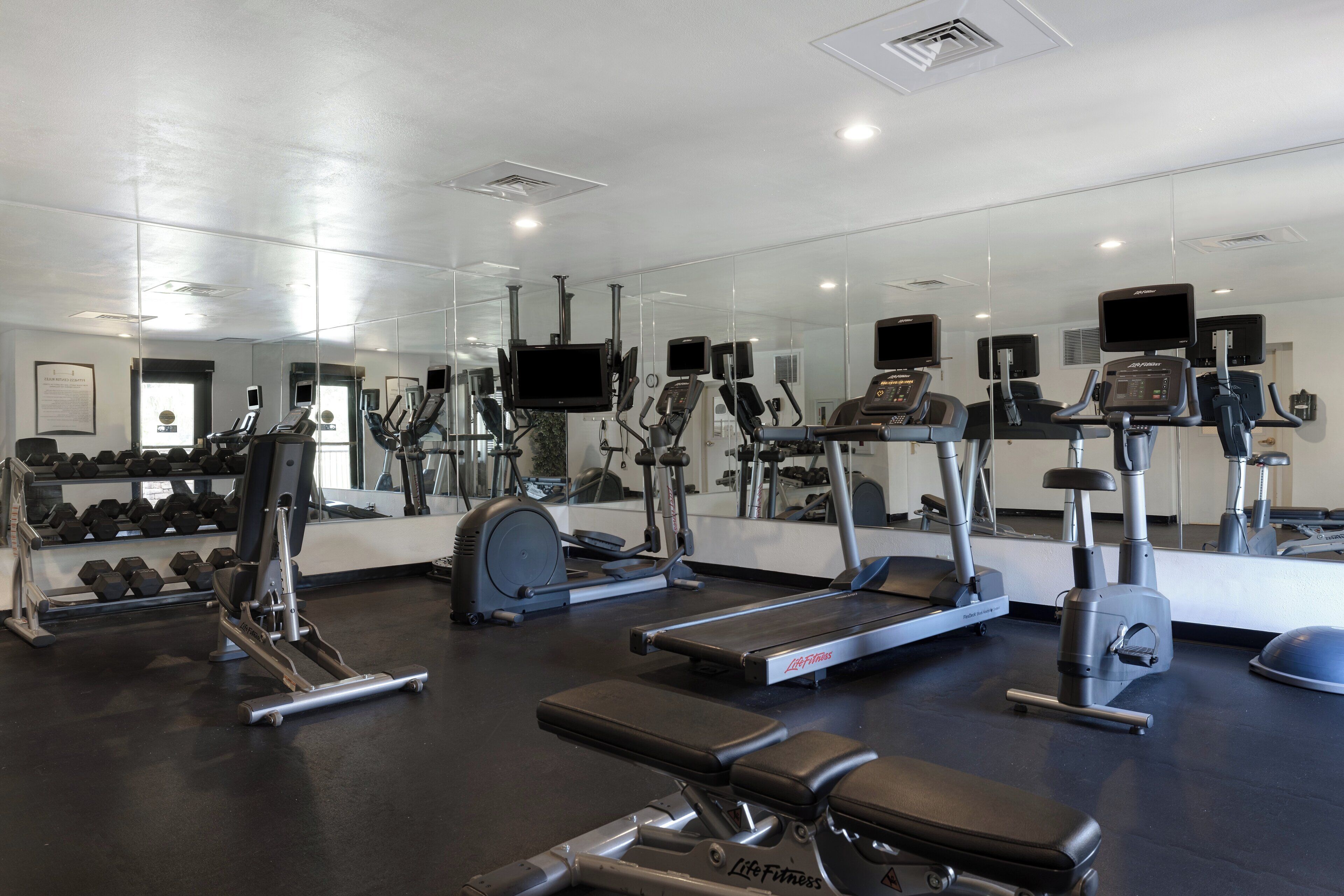 A gym with various exercise equipment, including treadmills, stationary bikes, and weight machines.
