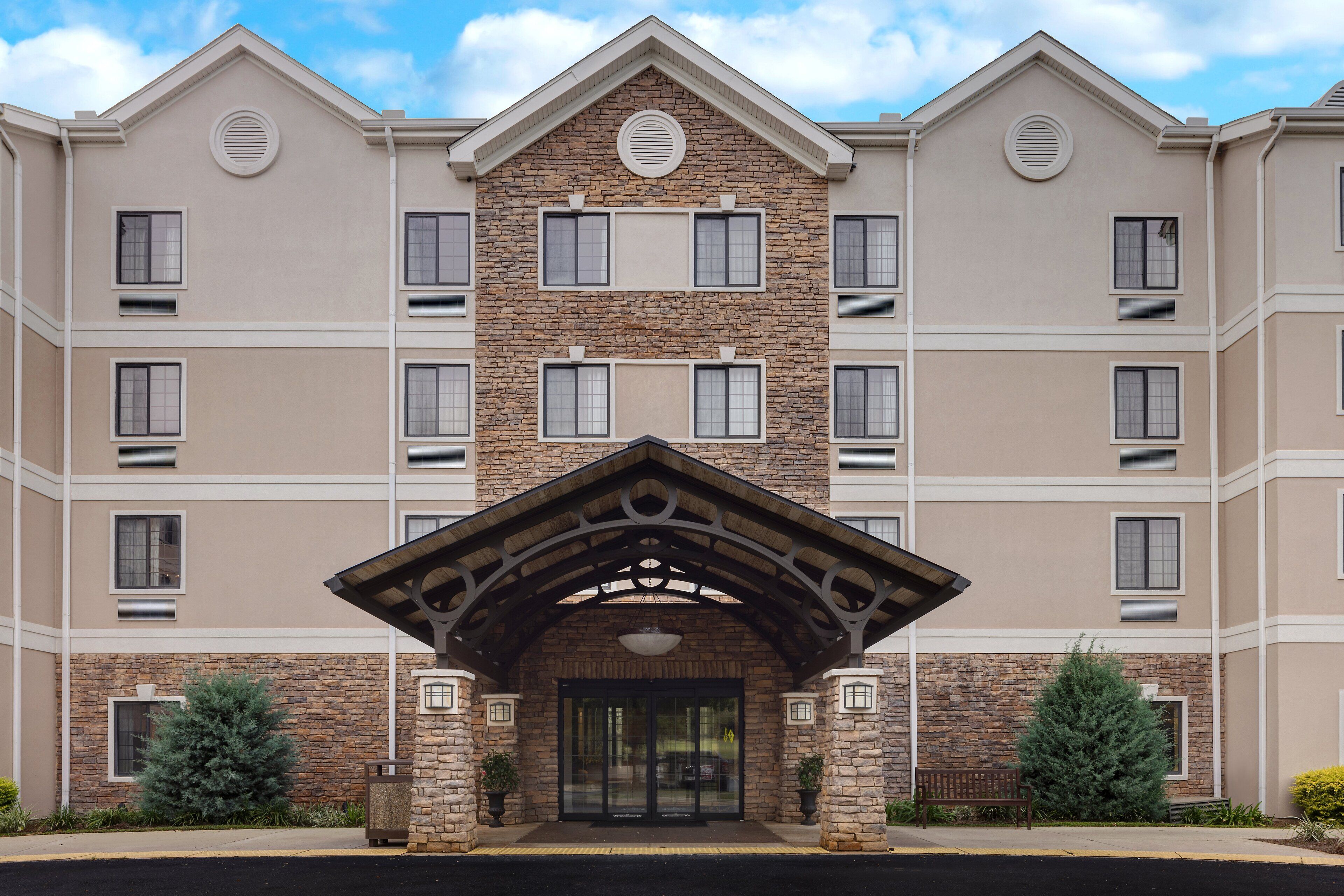 A multi-story hotel with a stone facade, a central entrance with a wooden canopy, and multiple windows.