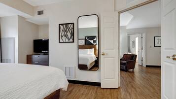 Una habitación de hotel con cama, televisión, cómoda y espejo.