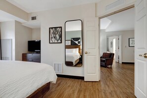 A hotel room with a bed, a television, a dresser, and a mirror. - Staybridge Suites Tallahassee by IHG (Tallahassee)