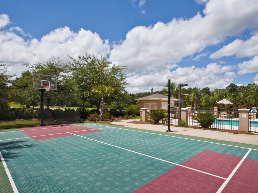 Una cancha de baloncesto al aire libre con piscina y zona de descanso.