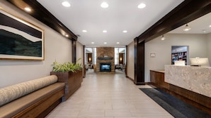 A modern lobby with a stone fireplace, wooden benches, a reception desk, and a large framed artwork on the wall. - Staybridge Suites Tallahassee by IHG (Tallahassee)