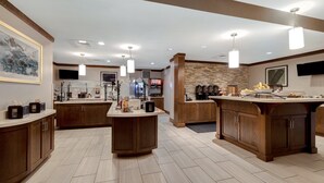 A spacious kitchen with wooden cabinets, a central island, and modern pendant lighting. - Staybridge Suites Tallahassee by IHG (Tallahassee)