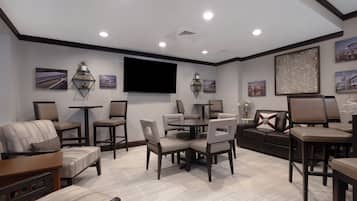 A modern living room with a flat-screen TV, comfortable seating, and a dining area.