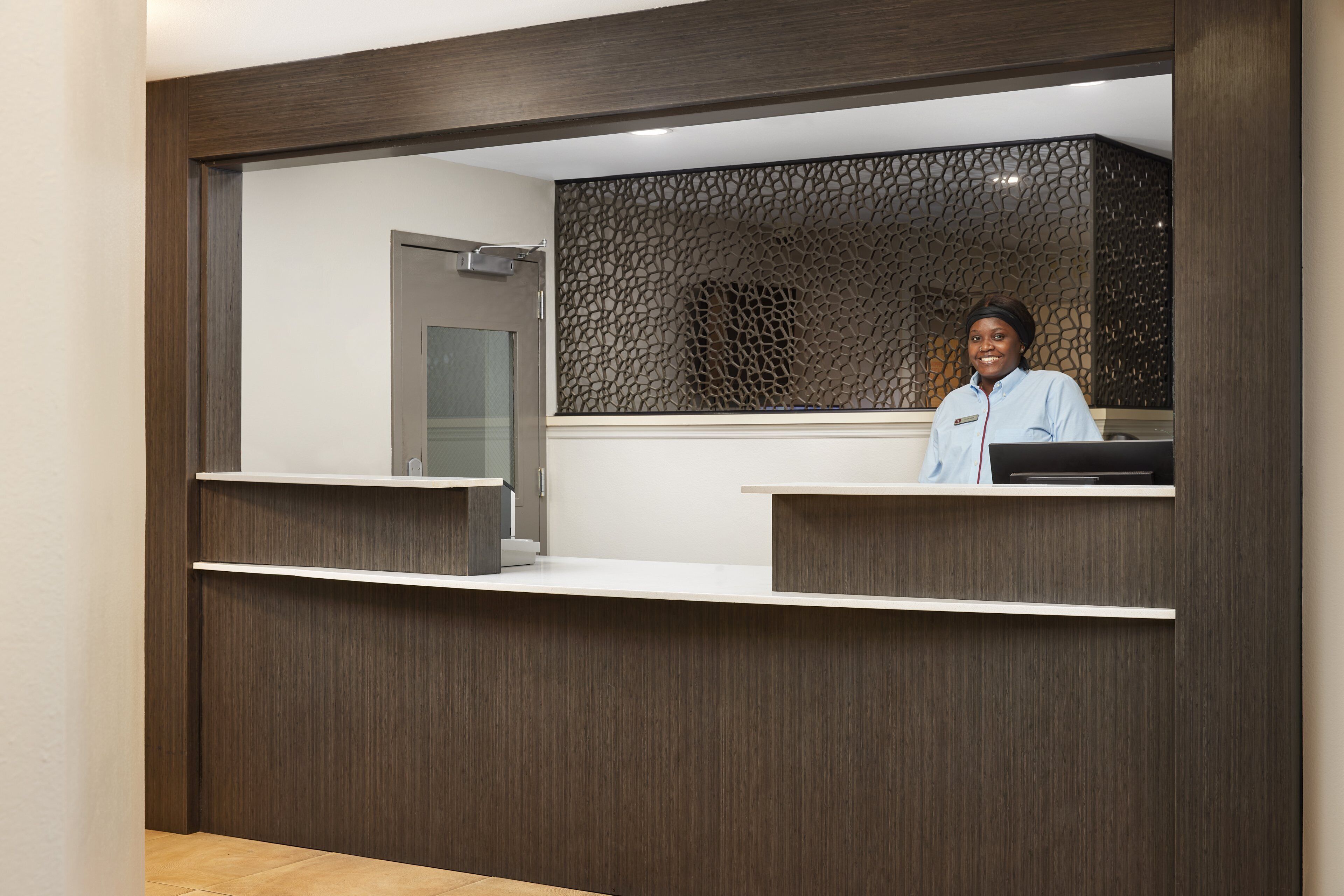 Una reception dal design moderno, con una porta in vetro e un pannello decorativo.