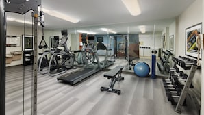 Un gimnasio con cintas de correr, elípticas, pesas libres y balones de ejercicio.