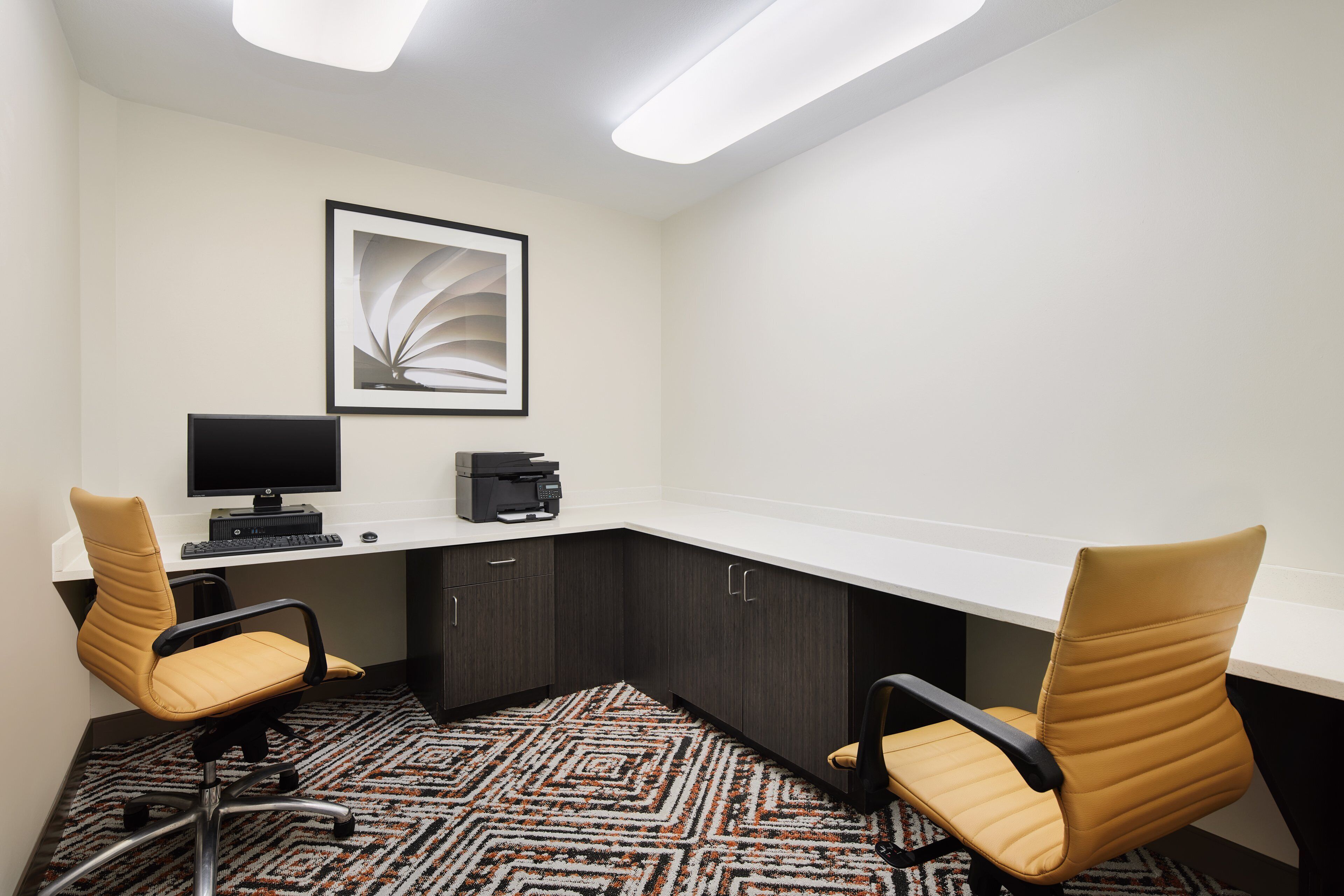 Une salle de conférence équipée de deux chaises, d’un bureau, d’un ordinateur et d’une imprimante.
