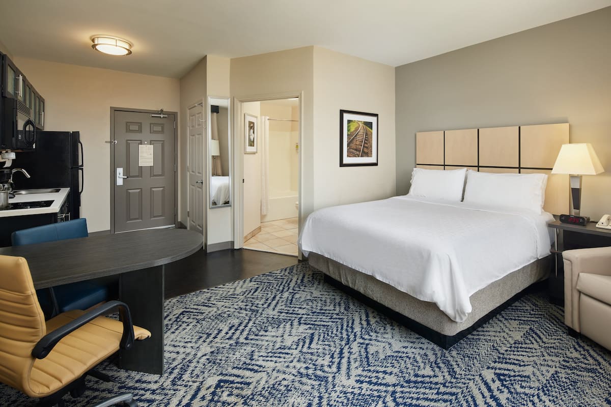 Habitación de hotel con cama, escritorio, silla y puerta de baño.