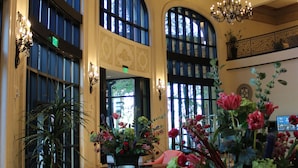 A lobby with large arched windows, a chandelier, and potted plants. - Argosy Casino & Hotel (Riverside)
