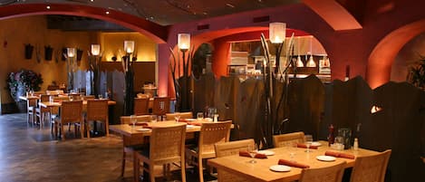 Un ristorante con tavoli e sedie in legno, pavimento piastrellato e colori caldi.