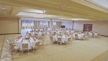 A large banquet hall with multiple round tables set for dining, arranged in rows.