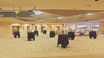A spacious hall with tables and chairs, directional signs for banquet rooms and casino, and an exit sign.