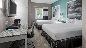 A hotel room with a TV, two beds, a desk, a chair, a window with curtains, and artwork on the walls. - Prairie Crest Medicine Hat (Medicine Hat)