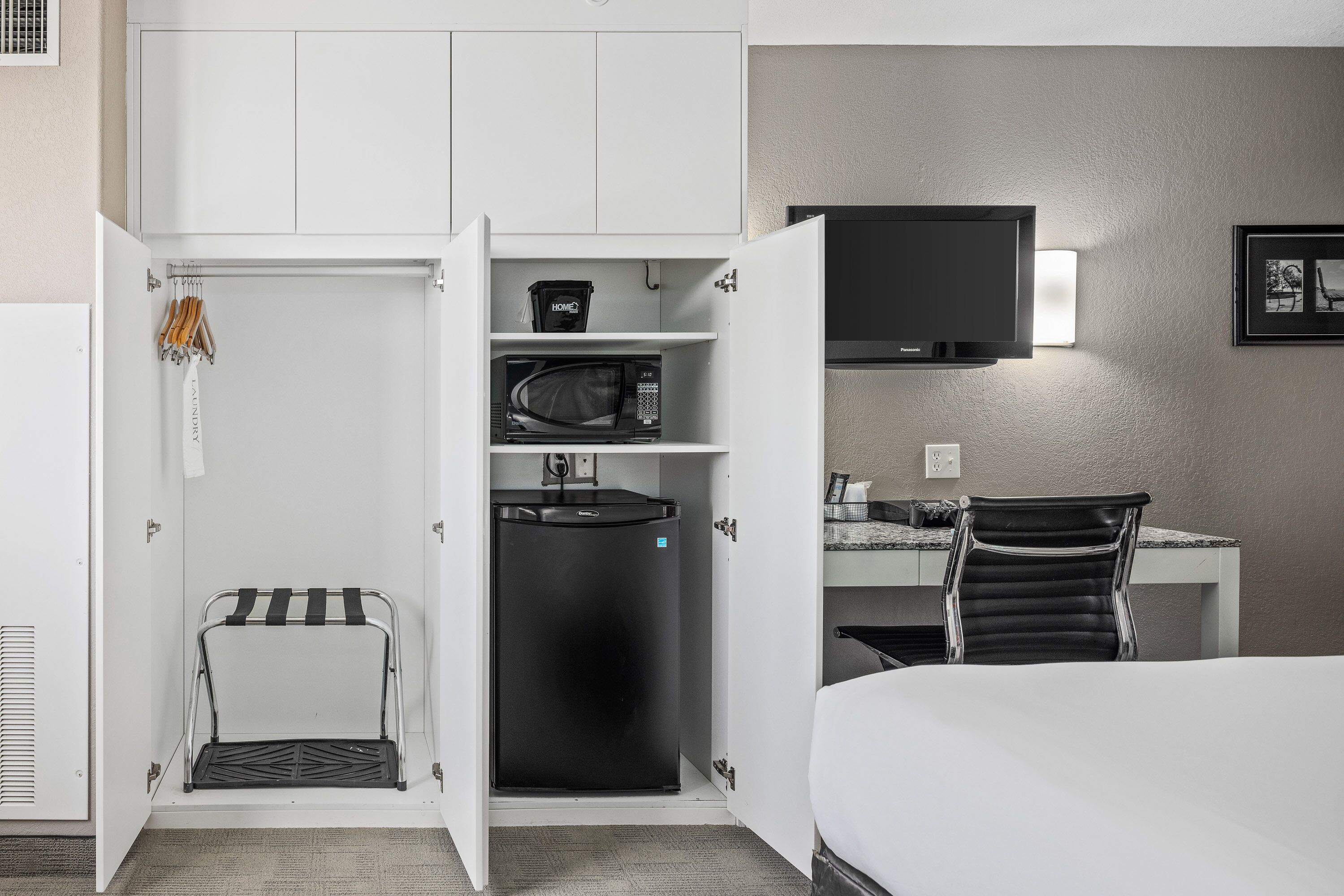 Une chambre d’hôtel de taille réduite, comprenant un lit, un bureau avec une chaise, un four à micro-ondes et un téléviseur.