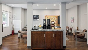 A modern kitchen area with a coffee station, a bulletin board, and seating arrangements. - Prairie Crest Medicine Hat (Medicine Hat)
