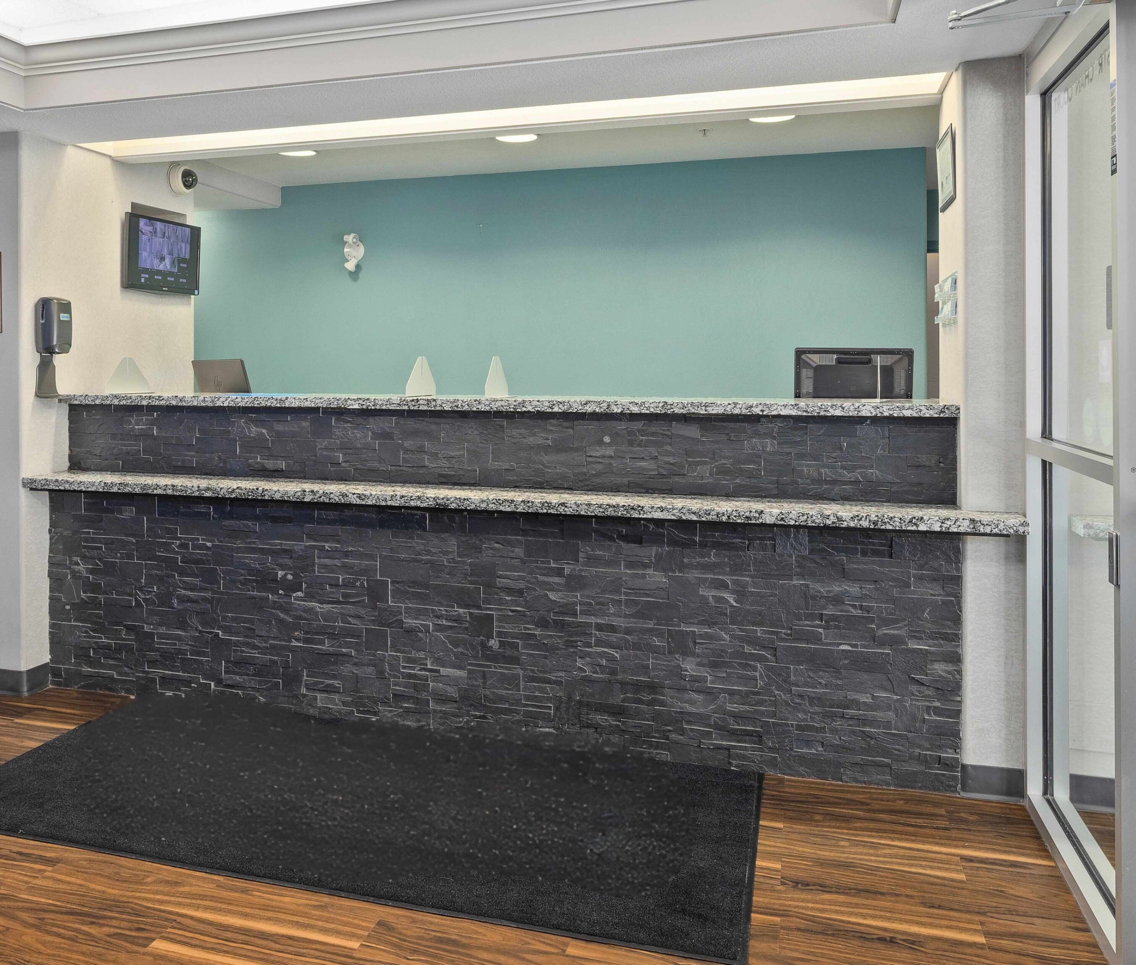 Una zona de recepción con pared de piedra, un tapete negro y pared color aguamarina.