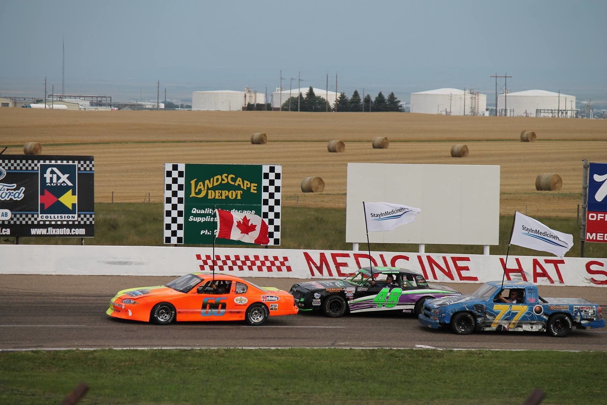 A race track with cars and a medical tent in the background.