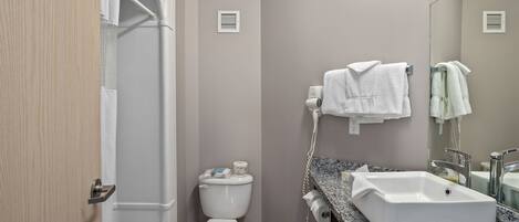Un baño con inodoro, lavamanos y barra para toallas.