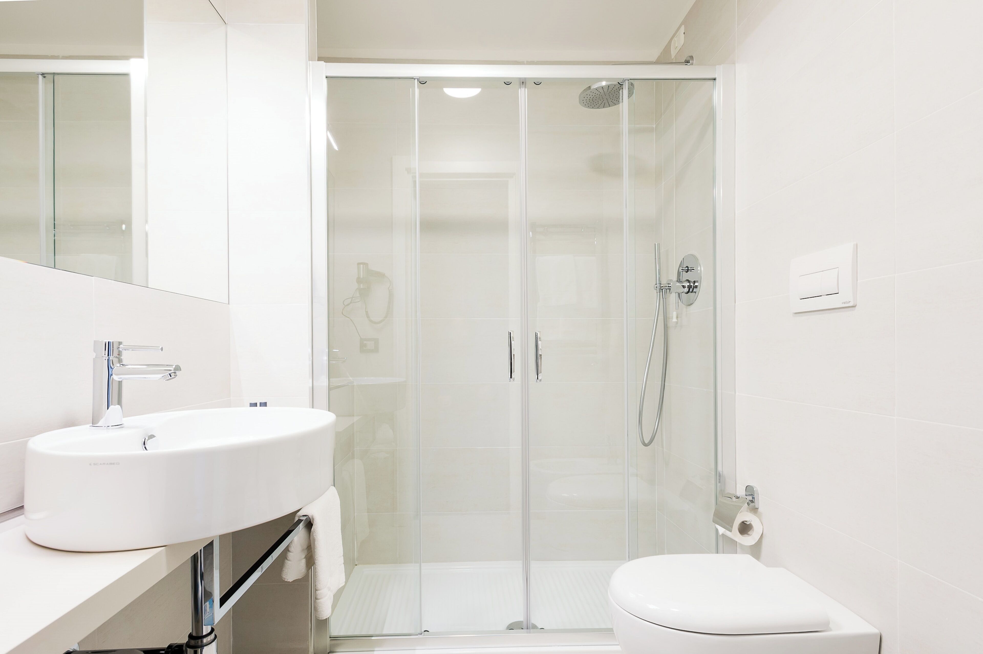 A modern bathroom with a white sink, toilet, and glass-enclosed shower.