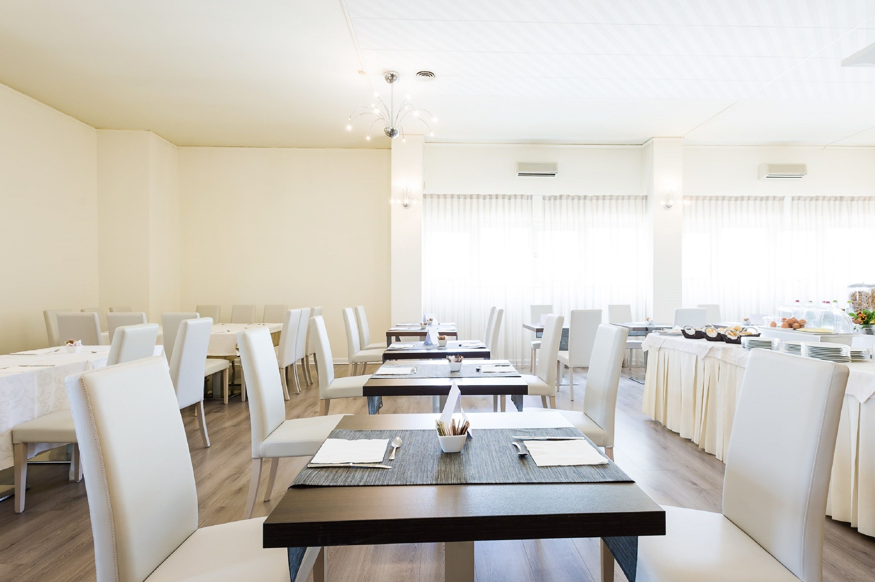 Un comedor amplio con varias mesas y sillas, dispuesto en un ambiente moderno y luminoso.